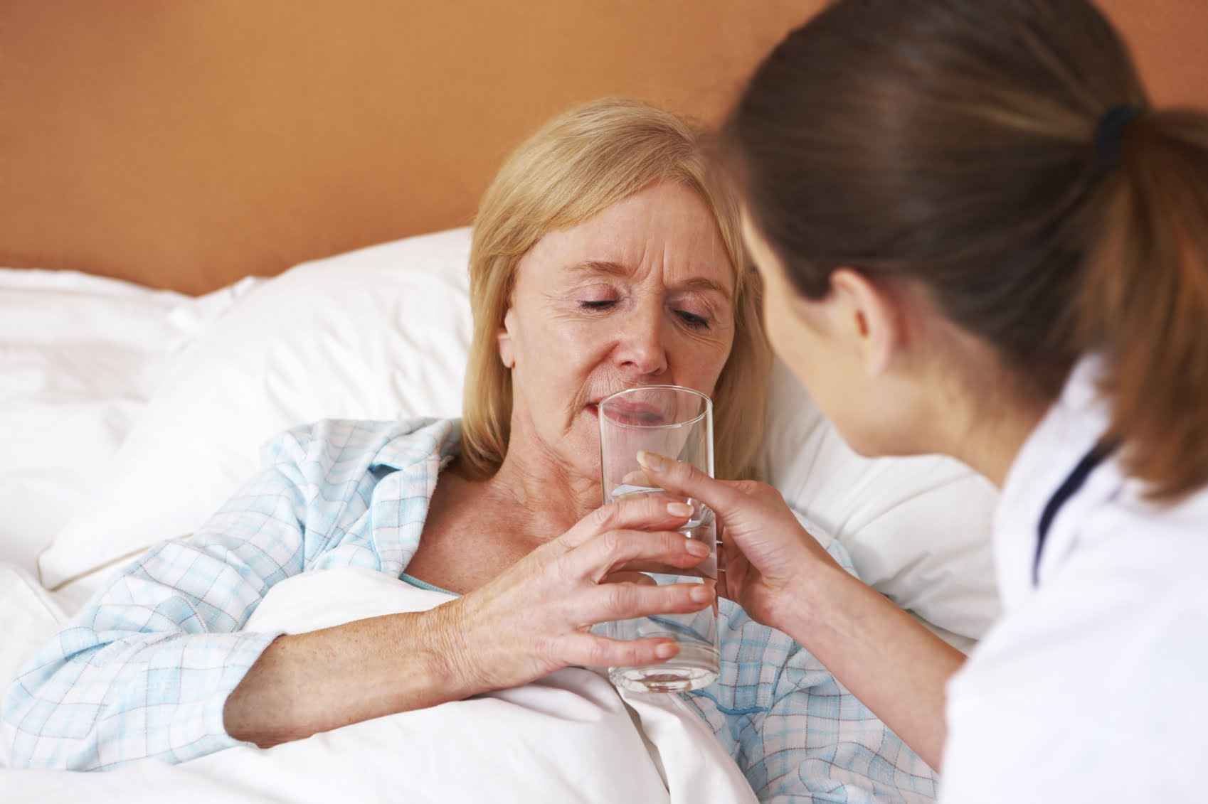 Nurse helping older woman drink
