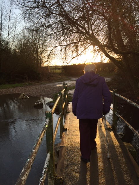 Mum walking away from the camera, over a bridge, at sunset