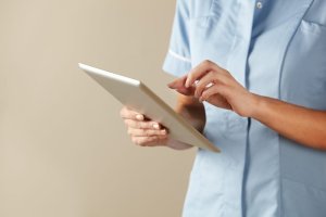 Nurse in pale blue shirt using computer tablet