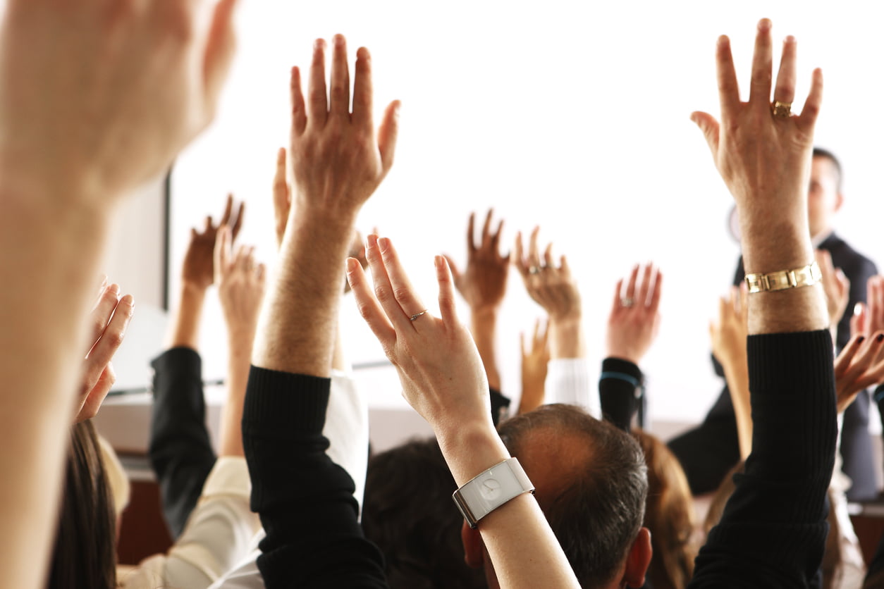 Voting audience, business spectators or students raising hands in