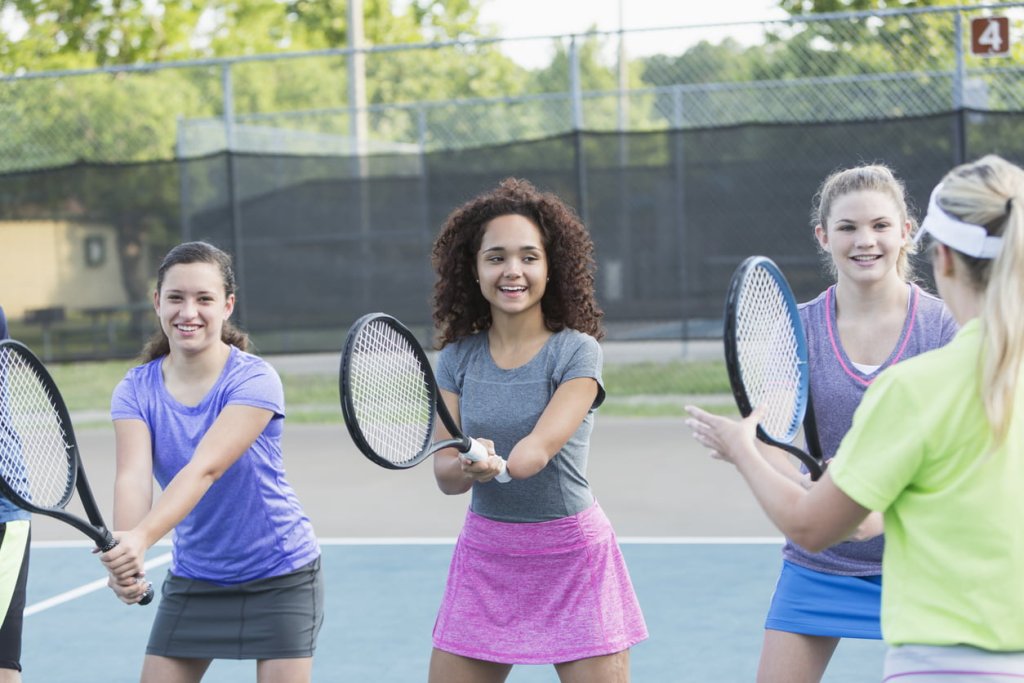 A group of young girls play tennis, one of them has no hand