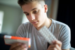 Young man reading medication label